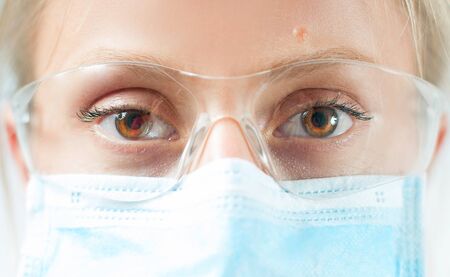 Close-up doctor's eyes with protective glasses and medical mask. Outbreaking Coronavirusの写真素材