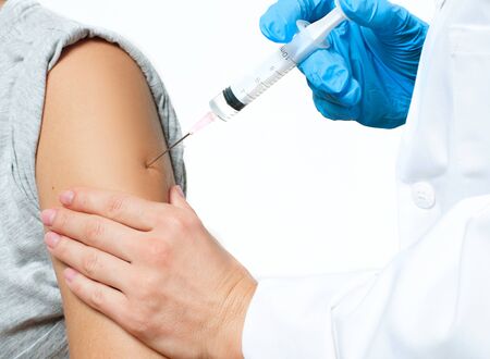 Doctor in protective gloves is injecting coronavirus vaccine to patient's arm for prevention, immunization and treatment from coronavirus infection, COVID-19の写真素材