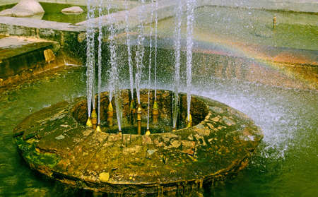 Rainbow in the fountain of city park, powerful streams of water, warm sun summer day. の写真素材
