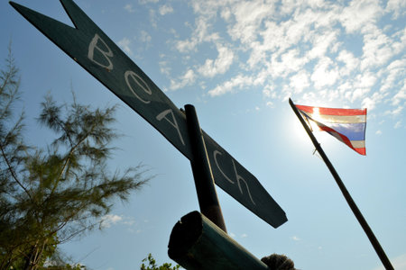Beach wooden sign with Thailand flag pointing to the closest beachの写真素材