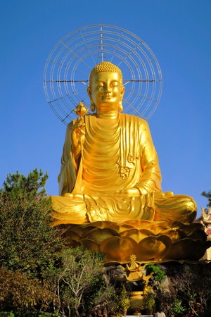 Giant sitting golden Buddha holding golden lotus at a Mahayana Buddhist temple in Dalat, Vietnamの写真素材