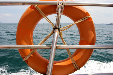 An orange lifebuoy on a boat in the blue sea