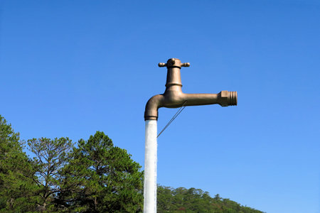 An oversized faucet in the middle of the lake appears to be floating above the water of a lake with...