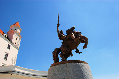 Statue of a horse riding Knight with a sword in front of Bratislava castle against a blue skyのeditorial素材