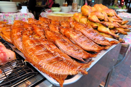 Row of grilled fish and hens are ligned up for buyers on a street market in Bangkok, Thailandの写真素材