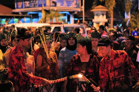 Yogyakarta, Indonesia - 7 October 2014:  258th city anniversary - One man helps another man reigniting his flame so he can march in a parade to celebrate tradition and unity at Marlioboro Street, Kota Yogyakartaのeditorial素材