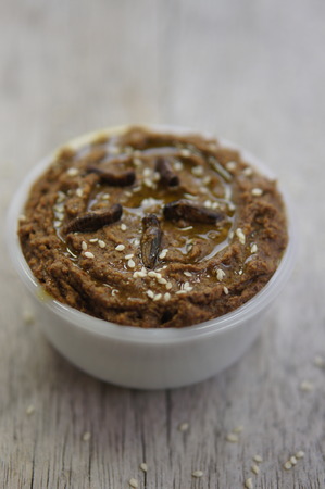 A white bowl of hummus fortified with protein rich cricket flour, and topped with sesame seeds and olive oilの写真素材
