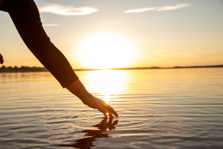 A woman doing yoga by the lake at sunset. The weather is nice. It is autumn. The mood is calm. The water is smooth. The sun sets!の写真素材