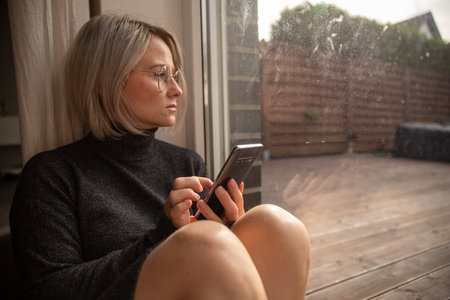 A sick woman looks into the distance. It is cold. She is thoughtful. She is at the window.