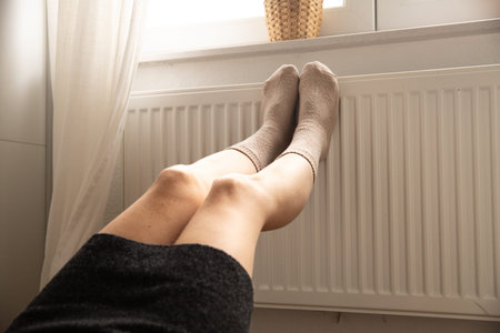 A woman warms herself on the heater. It is cold. She has a cold. She relaxes.の写真素材