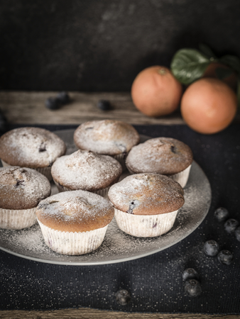 image shows 7 fluffy blueberry muffins decorated with sugar powder and blueberriesの写真素材
