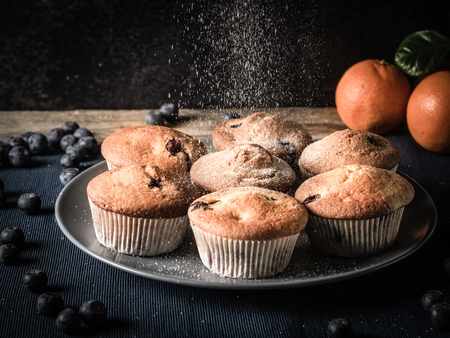 image shows fluffy blueberry muffins while powdering with sugar powderの写真素材