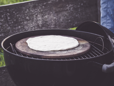 how to make homemade pizza using a grill or bbq - crust without toppings on a well floured pizza stoneの写真素材