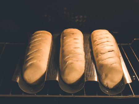 image shows 3 homemade baguettes or french bread in special baguette pan situated in baking oven...