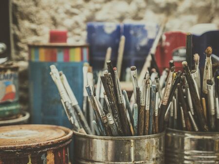 hundreds of used artist brushes in rustic vintage pot in front of stone wallの写真素材