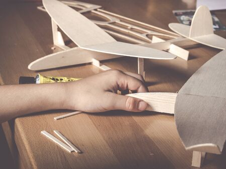 image shows a balsa wood aircraft model and kids hand holding a second wooden flight modelの写真素材