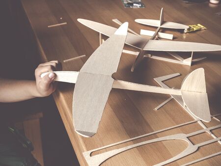 boys hand holding selfmade wooden airplane modelの写真素材