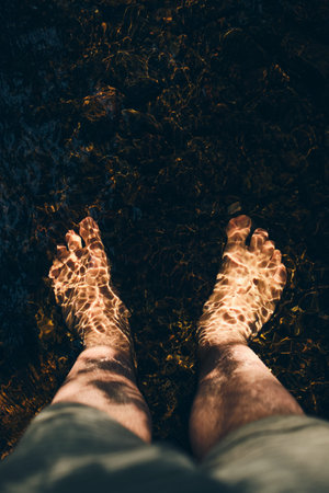 Submerged feet in river with ripples in sunshineの写真素材