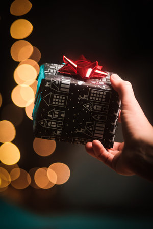 Hand with Crirstmas present in front of dark background