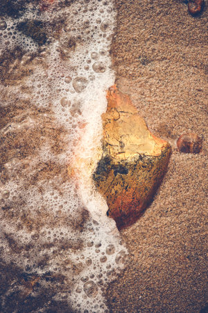 small rock getting hit by wave at beachの写真素材