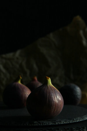 Purple figs on a black stone plate. Photo, background with fresh, juicy, ripe tropical fruits....