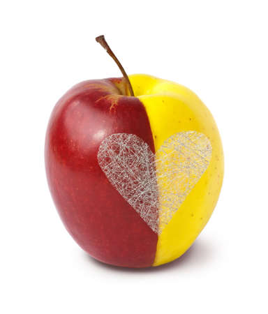 Two halves of apples merged together as a whole with silver heart on white background の写真素材