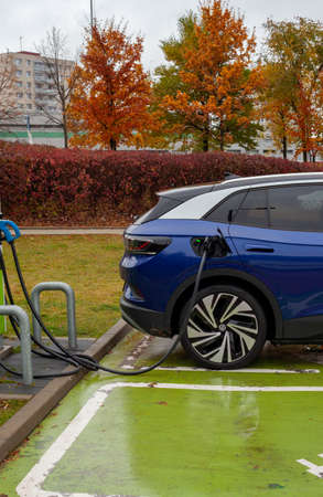 A dark blue electric SUV car charges in a parking lot.のeditorial素材