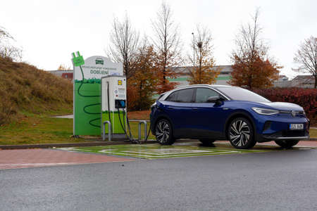 A dark blue electric SUV car charges in the parking lot of a Lidl supermarket.のeditorial素材