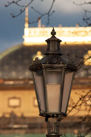 An art nouveau metal lamp post in the light of the winter sun with a gilded building in the blurred background. The sky is black.の写真素材