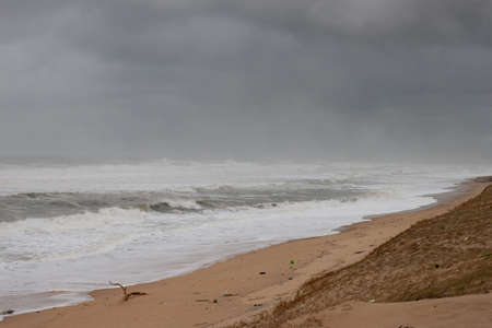 The waves break towards the beach, the ocean is raging, the sky is very dark and threatening. the beach has practically disappeared.の写真素材