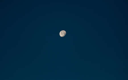 the moon three quarters full in a dark blue sky without a cloud. The craters of the moon are visible.の写真素材