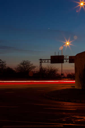 A star shines in the night sky. Red streaks of lights indicate the speed of the carsの写真素材