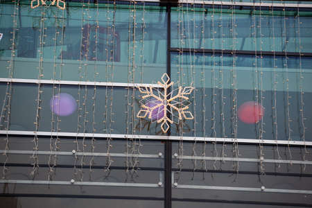 A small snowflake-shaped garland hangs on a shopping center facade to celebrate Christmas.の写真素材