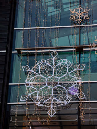 Two snowflake-shaped garlands hang on a shopping center facade to celebrate Christmas.の写真素材
