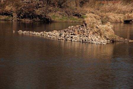 Pebbles have formed a mini island in the middle of the river. Everything is yellow brown giving an impression of a serene calm still life.の写真素材