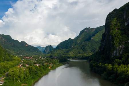 Expansive view of the Nam Ou river flowing beside the village of Nong Khiaw, Laos, framed by steep...