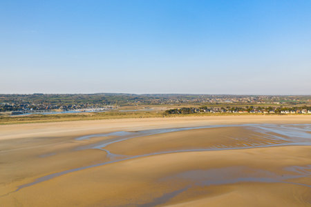 Expansive view of Grande Plage de Barneville with golden sand, shallow tidal pools, and a distant...