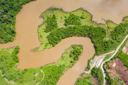 Aerial view of winding muddy waterways and lush green islands along the Nam Theun 2 Reservoir in central Laos. The landscape features irregular shorelines, dense vegetation, and a mix of natural textures under bright daylight.の写真素材