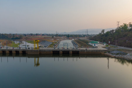 A modern hydroelectric dam releases water into a straight canal bordered by engineered embankments...