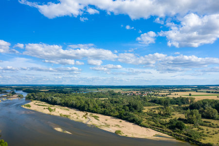 Expansive aerial view of the Loire River meandering past sandy banks, dense green forest, and open...