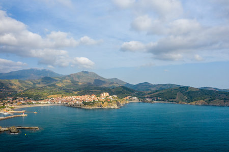 Aerial view of Banyuls-sur-Mer with a sweeping bay, terracotta-roofed village, and rolling green...