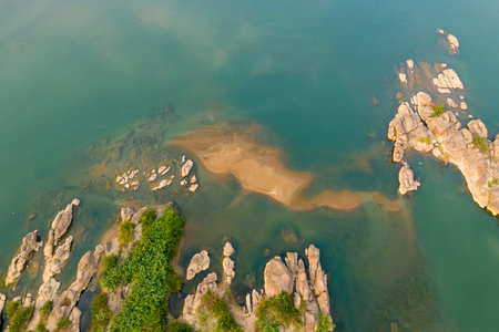 Aerial perspective reveals smooth sandstone outcrops, scattered rocks, and sandy shallows in the...