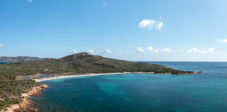 Wide panoramic image of Spiaggia la Salinedda, Sardinia, showing a sweeping bay with turquoise...