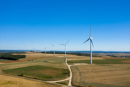 Aerial view of modern wind turbines rising above expansive agricultural fields near Oisy, under a...