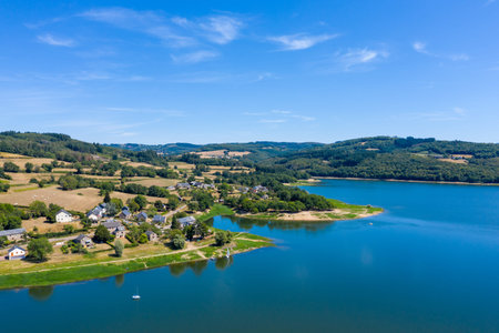 Aerial view of a small rural village nestled beside the vivid blue waters of Panneciere-Chaumard...