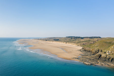 Aerial perspective of an expansive sandy beach meeting rugged cliffs at Cap de Carteret, with...