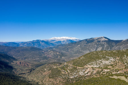 Distant snow-capped summit of Mont Parnasse rises above sprawling green valleys and rugged hills...