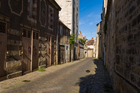 Narrow cobblestone lane lined with historic stone buildings and wooden doors in the old town of...
