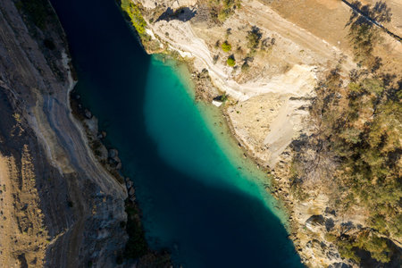 Aerial top-down view of the Corinth Canal featuring vivid turquoise water, steep rocky banks, and...