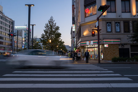 Himeji, Japan - November 1, 2023: People wait at a crosswalk in the city center near a 7-Eleven...